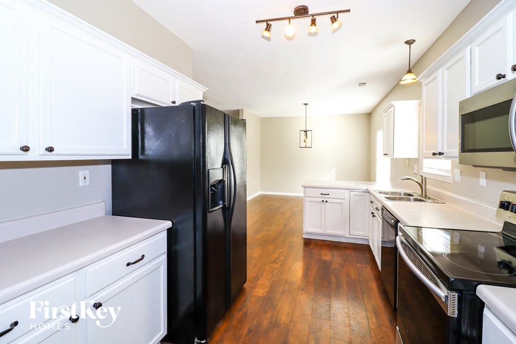 A kitchen with a black fridge and white cabinets.