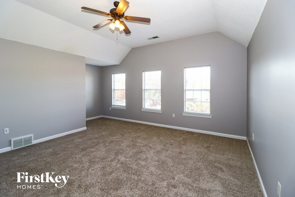 A spacious room with a ceiling fan and carpeted floor.