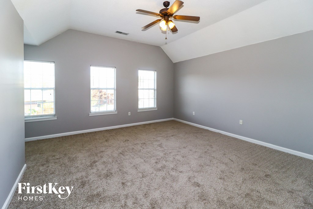 A spacious room with a ceiling fan and carpeted floor.