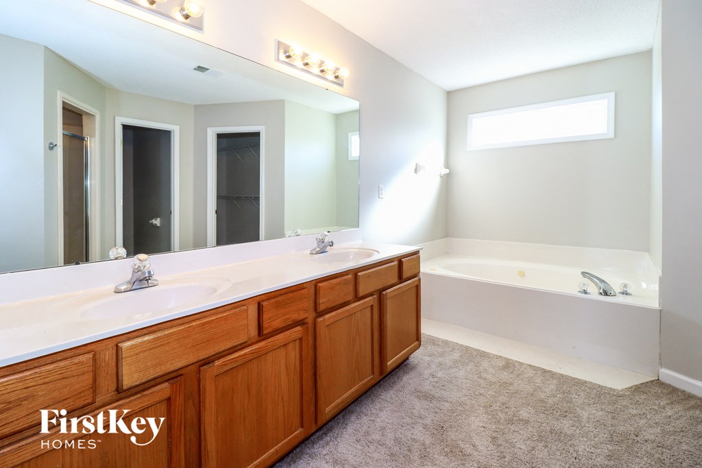A bathroom with a large mirror and wooden cabinets.