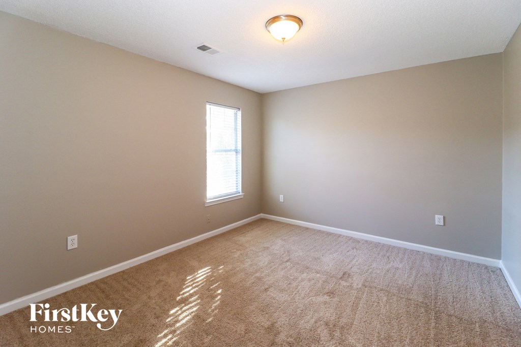 A room with a carpeted floor and a window letting in sunlight.
