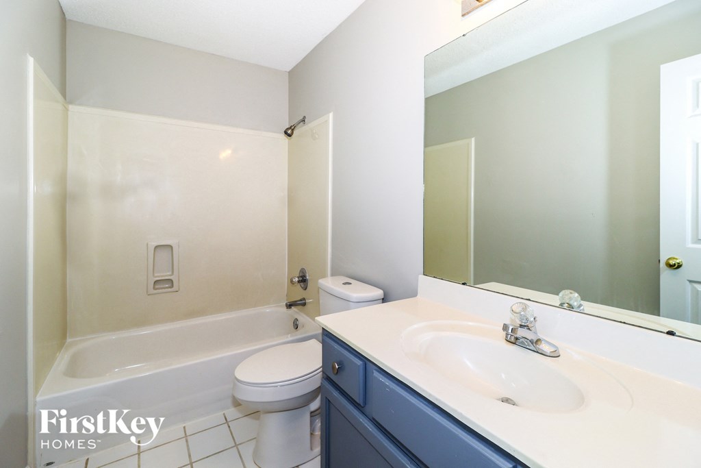 A white bathroom with a white toilet, white sink, and a white tub.