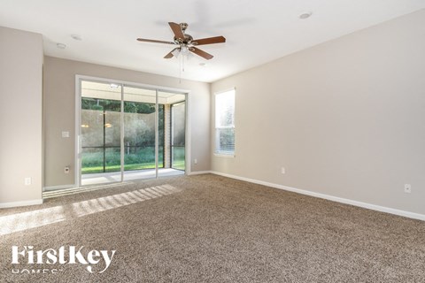 an empty living room with a ceiling fan and a window
