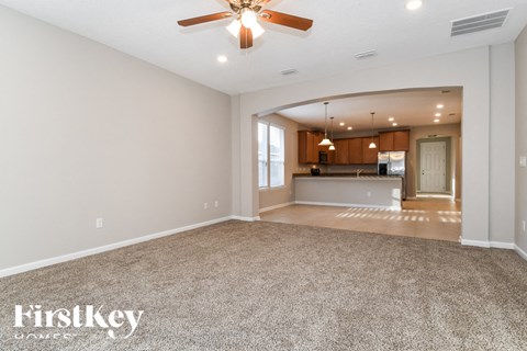 an empty living room and kitchen with a ceiling fan
