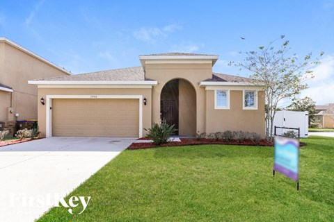 A house with a garage and a sign in front of it.