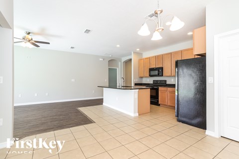 A kitchen with a black refrigerator and wooden cabinets.