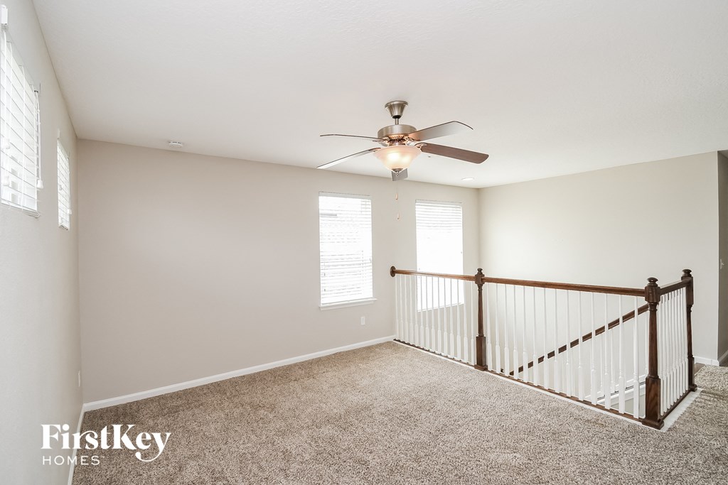 a landing with a ceiling fan and a stair case