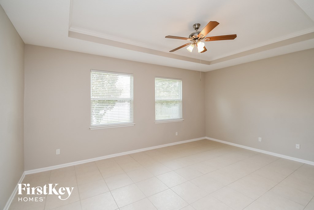 an empty living room with a ceiling fan and two windows