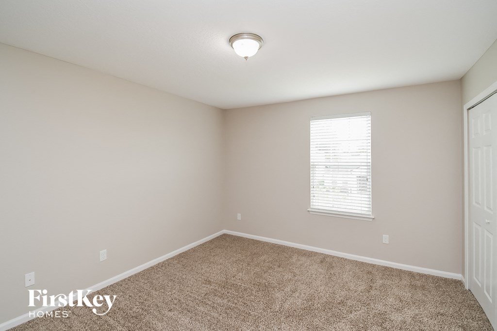 a spacious bedroom with carpeted flooring and a window