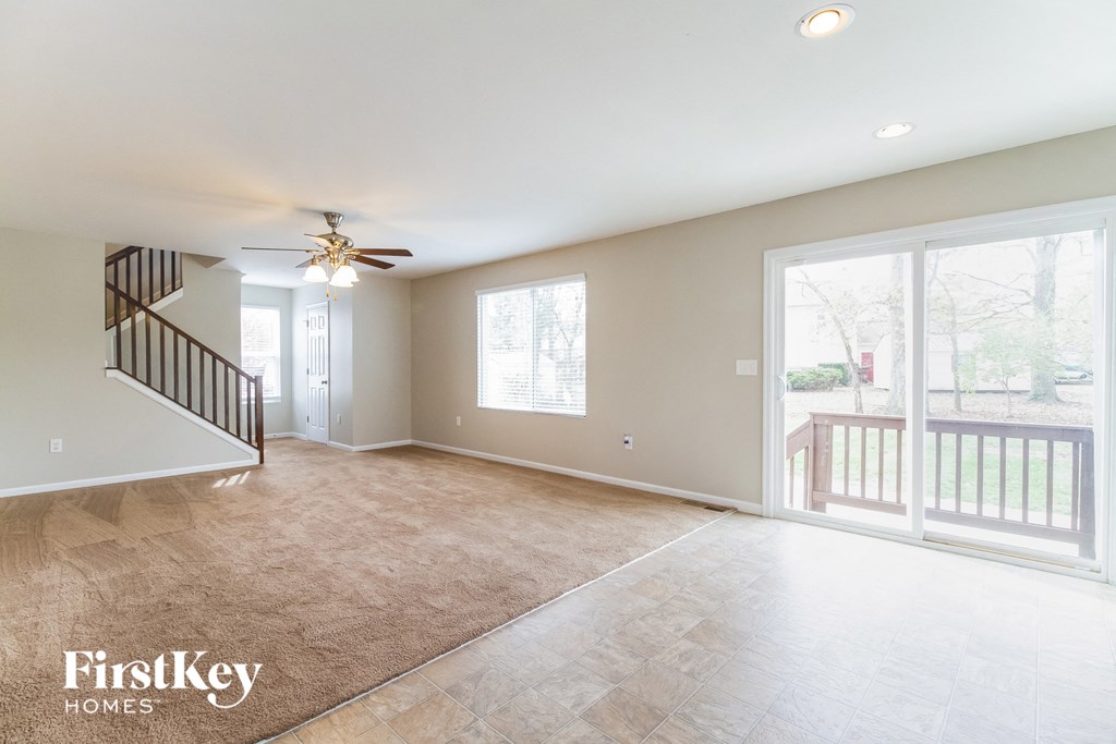 A spacious living room with a staircase and sliding glass doors.