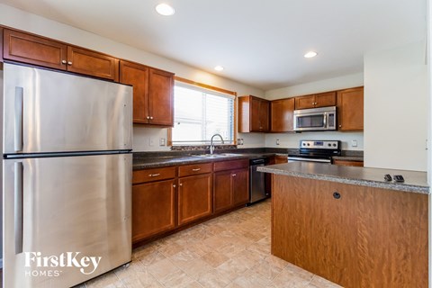 A kitchen with a stainless steel refrigerator and wooden cabinets.
