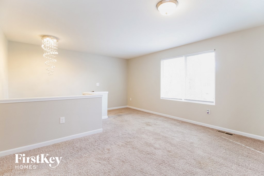A spacious room with a carpeted floor and a window letting in natural light.