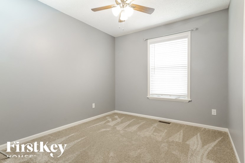the bedroom of an empty house with a ceiling fan and a window