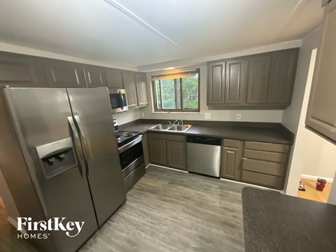 A kitchen with a stainless steel refrigerator and a window.
