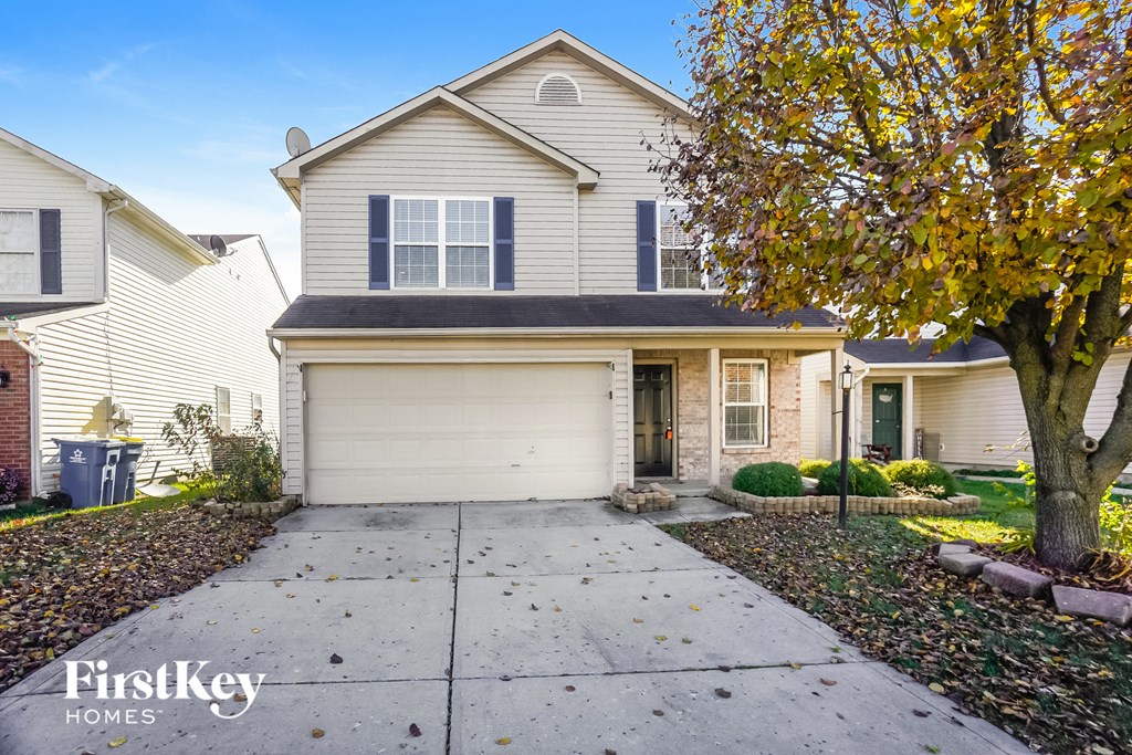 a white house with a white garage door and a tree