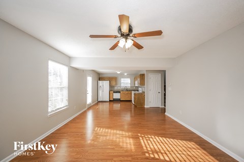an empty living room and kitchen with a ceiling fan