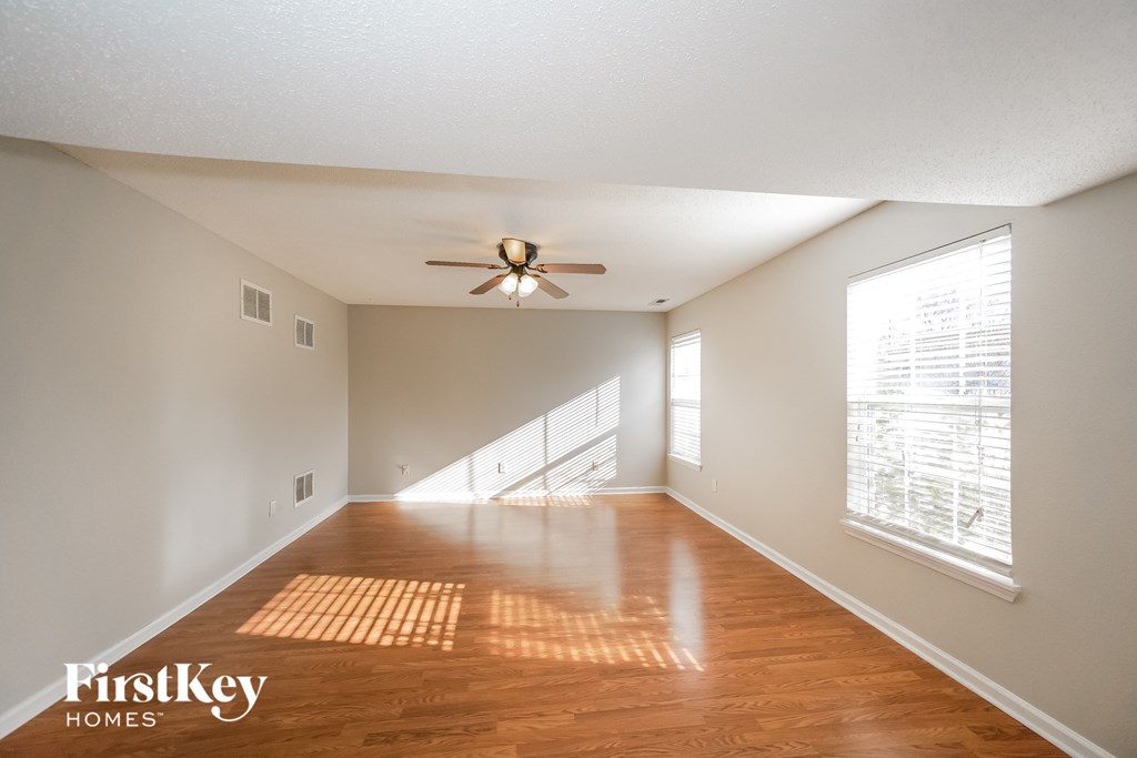 an empty living room with wood floors and a ceiling fan