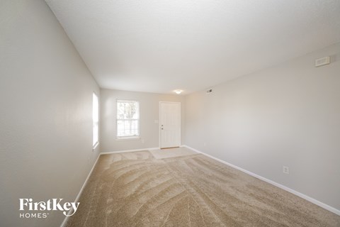 a spacious living room with carpet and a white door