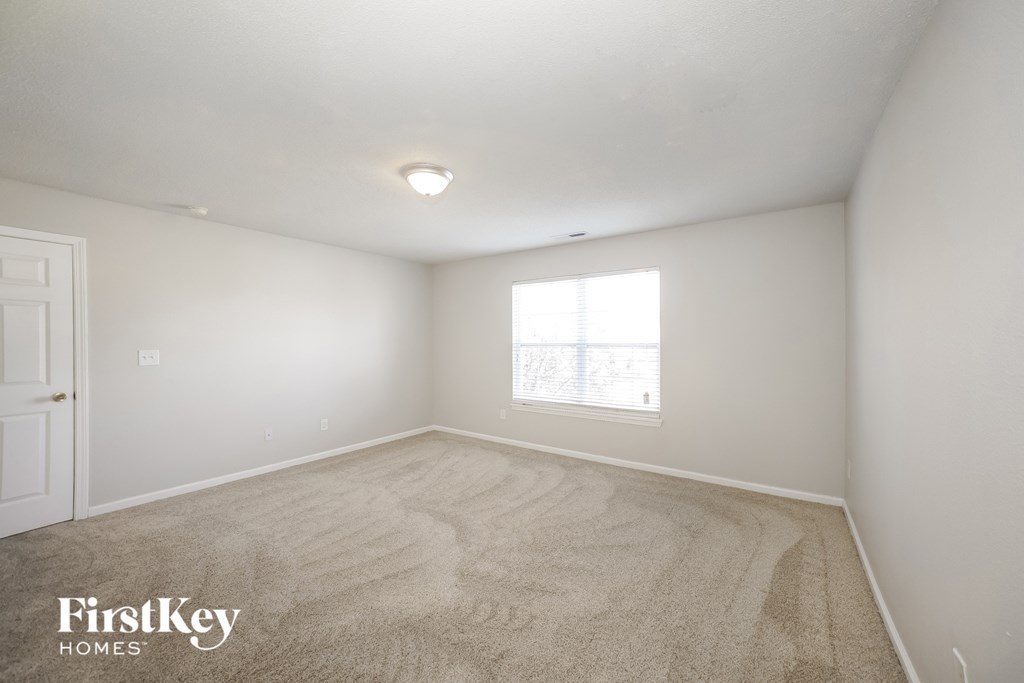 a spacious living room with carpet and a window