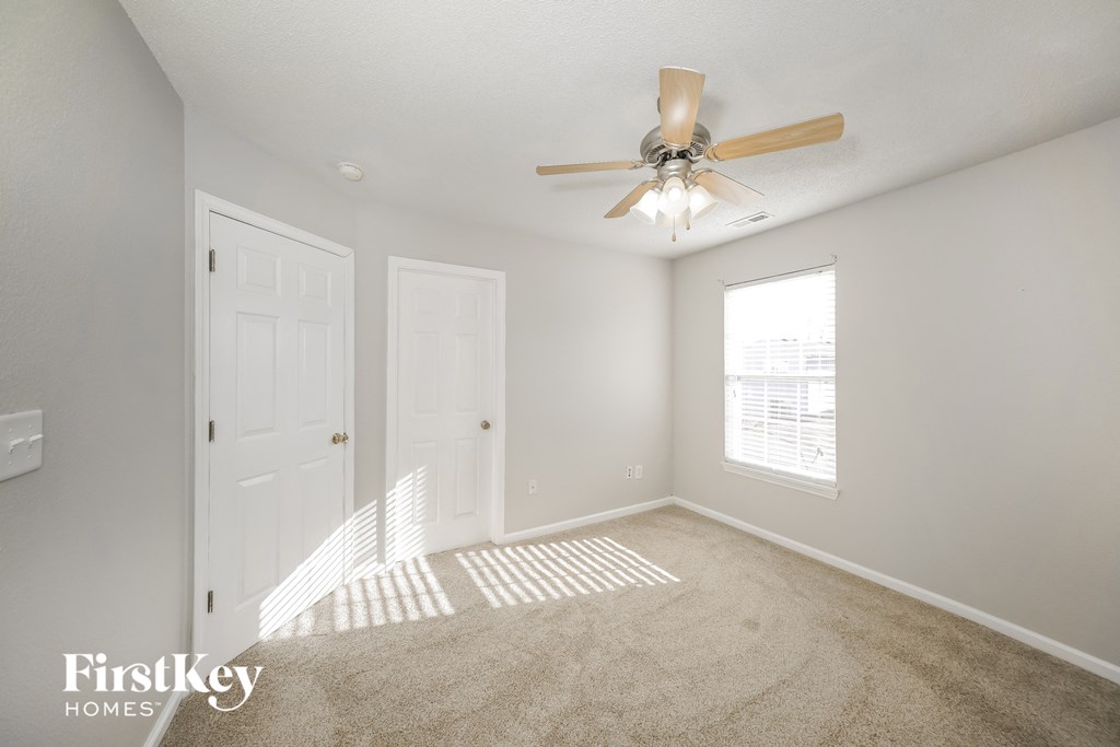 an empty bedroom with a ceiling fan and a window