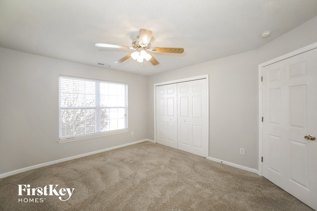 a bedroom with carpeted flooring and a ceiling fan