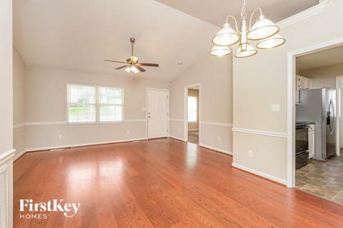 A spacious room with wooden floors and a ceiling fan.