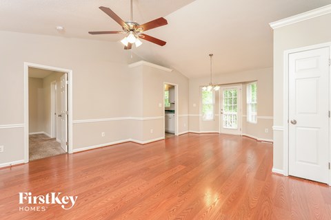 A spacious room with a ceiling fan and wooden flooring.