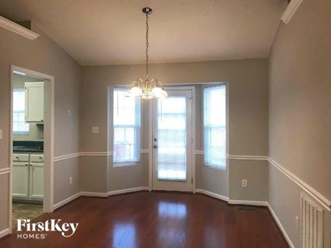 A room with a chandelier and a view of a kitchen.