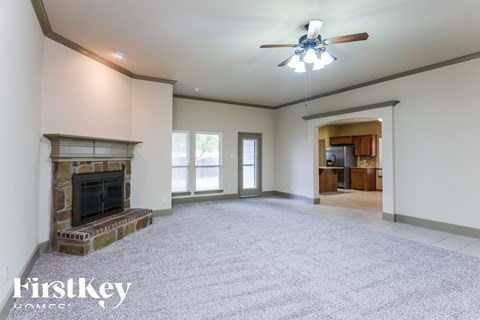 A spacious living room with a fireplace and a ceiling fan.