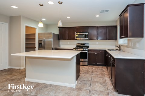 a kitchen with a large white island and dark wood cabinets