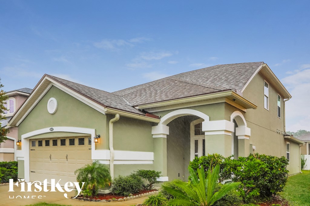 a green house with a driveway and a garage