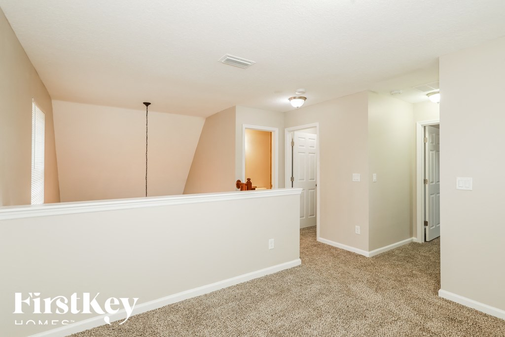 a spacious living room with a white wall and carpeted floor