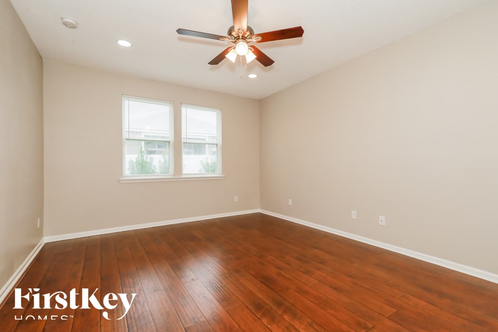 a living room with wood floors and a ceiling fan