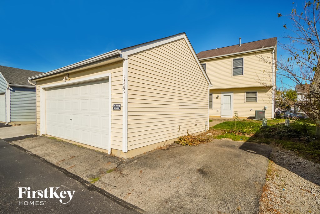 A beige house with a white garage door is for sale.