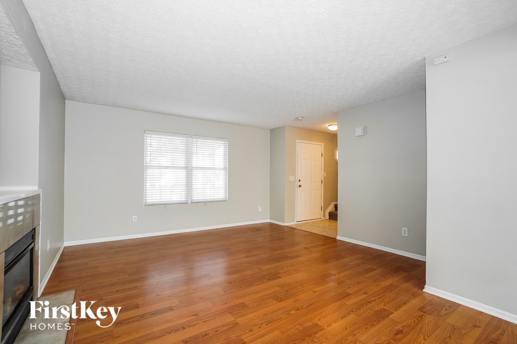 A room with wooden floors and a window with blinds.
