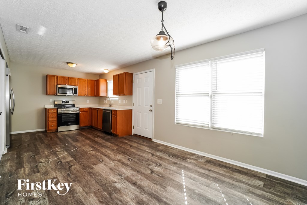 A kitchen with wooden cabinets and a microwave is shown.