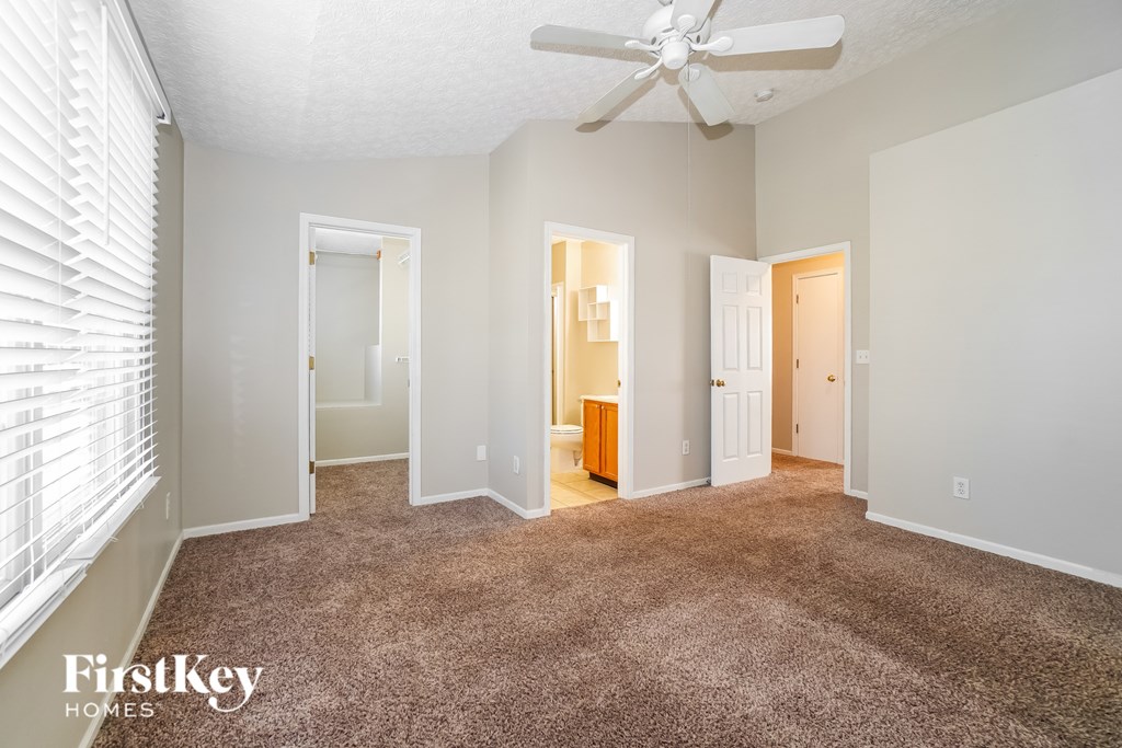 A spacious room with a carpeted floor and a ceiling fan.
