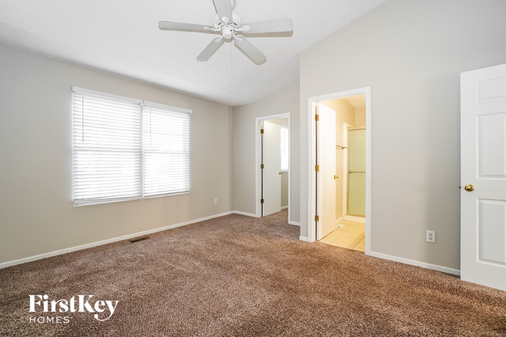 A room with a carpeted floor and a ceiling fan.