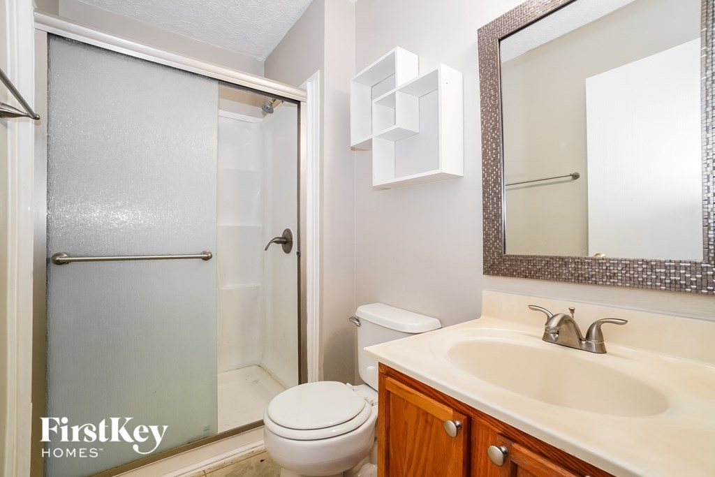 A bathroom with a toilet, sink, and mirror.
