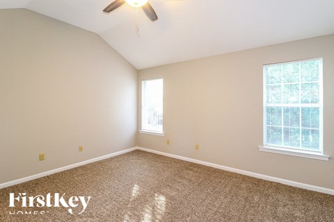 a bedroom with carpet and two windows and a ceiling fan