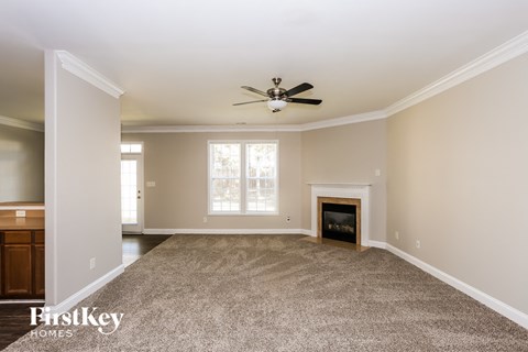 A spacious living room with a fireplace and a ceiling fan.