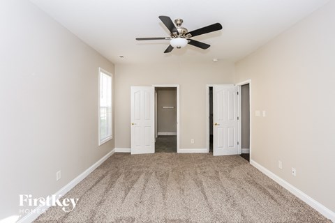 A spacious room with a ceiling fan and carpeted floor.