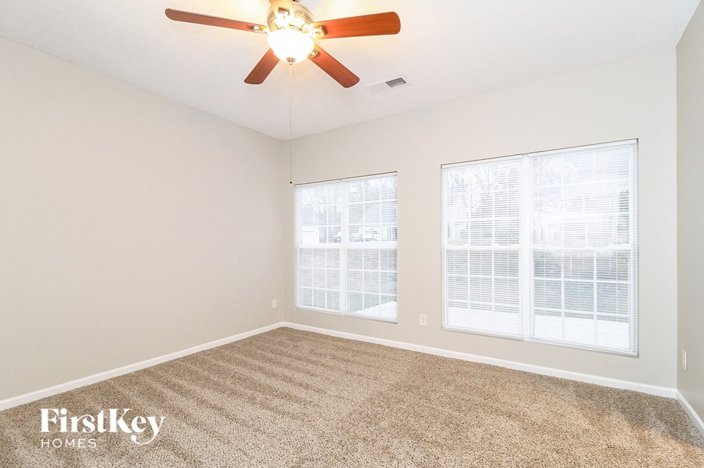 a bedroom with two windows and a ceiling fan