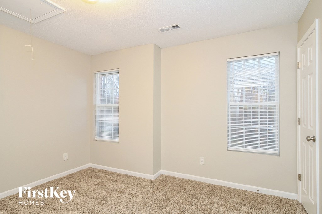 a bedroom with a carpeted floor and two windows