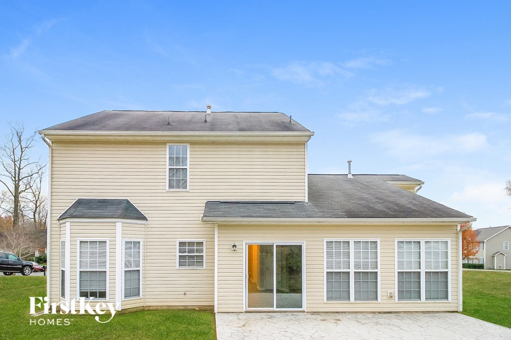 a yellow house with white windows and a driveway