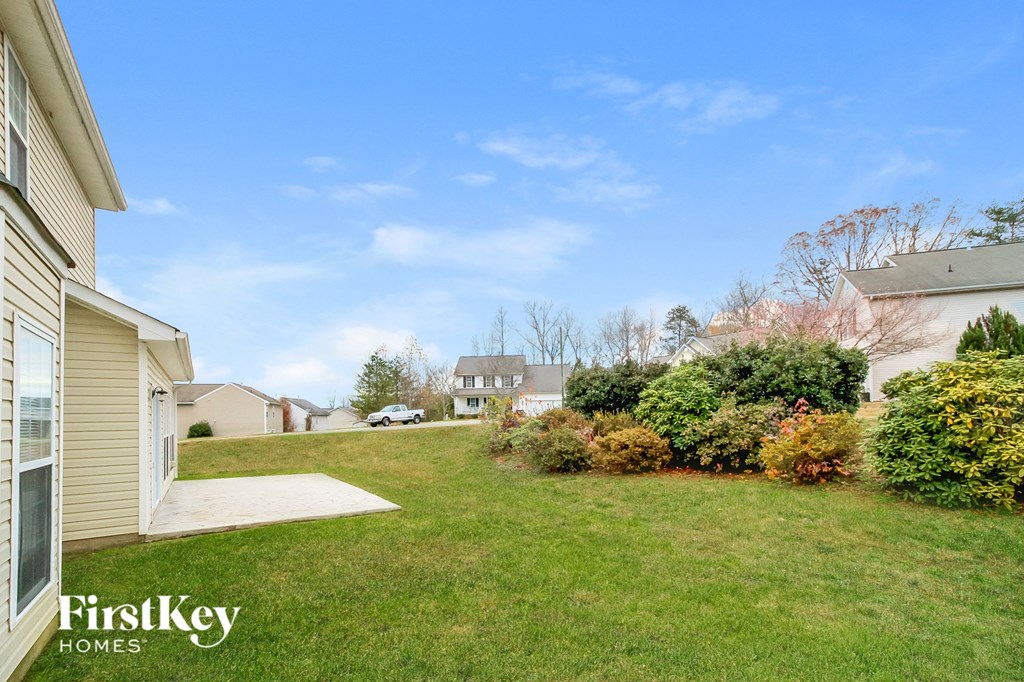 the backyard of a house with a green lawn and shrubs