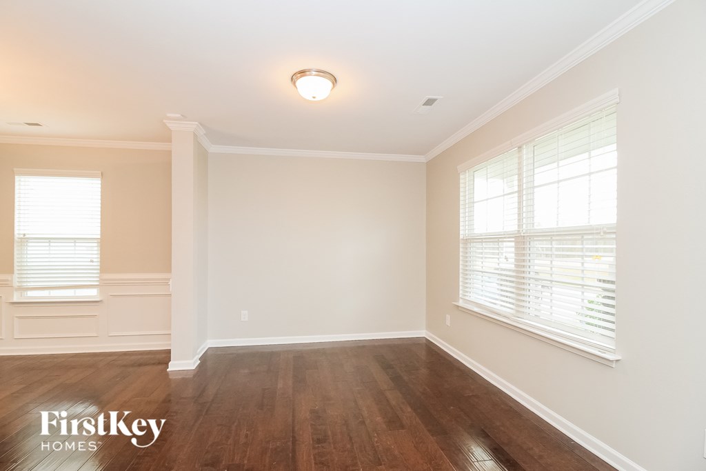 A room with wooden floors and white walls, with a window on the left side.