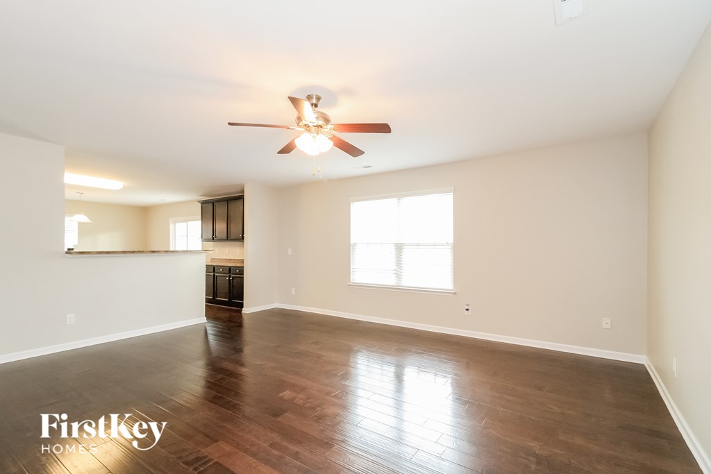 A spacious room with a ceiling fan and hardwood floors.