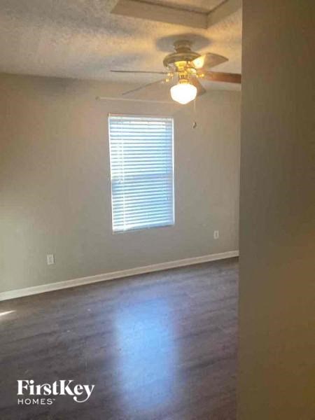 A room with a ceiling fan and a window with blinds.