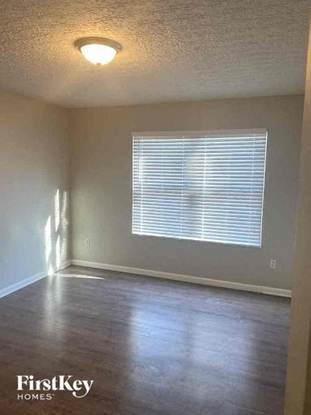 A room with a window covered by blinds and wooden flooring.